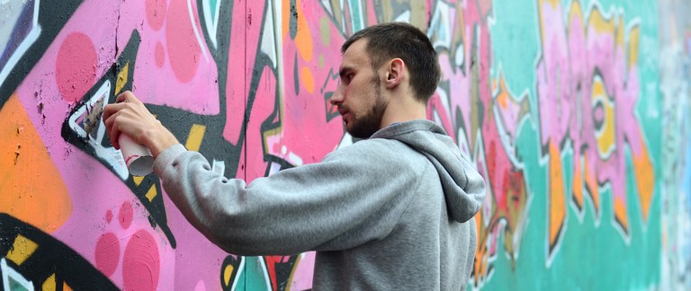 young-guy-gray-hoodie-paints-graffiti-pink-green.jpg.jpeg